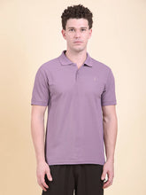 Man wearing a purple polo t-shirt (DCYPHR Men's Element Polo - Dusk Plum) against a beige background.